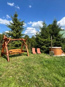 two chairs and a wooden swing in a field at Carpathian cabin - Icelandic horses - Hestur Ivo in Izvoare