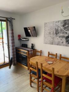a dining room with a wooden table and a kitchen at La Marmotine in Le Dévoluy