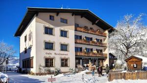 a building with people standing outside of it in the snow at Hotel Dahoam by Miha in Westendorf