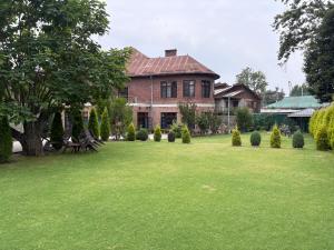 una grande casa con un prato verde davanti di Heritage Mansion a Srinagar