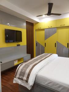 ein Schlafzimmer mit einem Bett und einem TV an einer gelben Wand in der Unterkunft KRIPA KUNJ -Cozy Stay like home in Varanasi