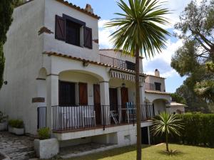une maison avec un palmier devant dans l'établissement Casa Vacacional Tranquila con Piscina, Jardín y Cerca de la Playa en L'Estartit - ES-323-29, à L'Estartit