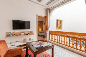 un salon avec une télévision et une table dans l'établissement RIAD Miel & Une Nuit, à Marrakech
