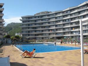 eine Frau, die auf einem Stuhl neben einem Swimmingpool sitzt in der Unterkunft Apartamento en Primera Línea Playa con Piscina y Vista al Mar - L'Estartit, Centro - ES-323-71 in Torroella de Montgrí