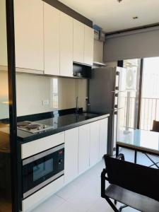eine Küche mit weißen Schränken und einer schwarzen Arbeitsplatte in der Unterkunft Central Pattaya Close To The Sea in Pattaya