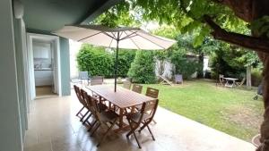 a table and chairs with an umbrella on a patio at Loue maison 10 couchages à La Rochelle avec jardin, proche plage in La Rochelle