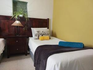 a bedroom with two beds and a table with a lamp at The Anvil Rest Cottage in Calitzdorp