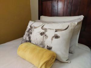 a pillow with a picture of a cow on a bed at The Anvil Rest Cottage in Calitzdorp