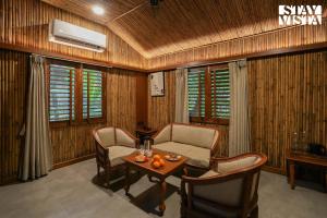 un soggiorno con un divano, sedie e un tavolo di StayVista's Timber Cottage - Cozy Cottages with Indoor Games a Wādhiware