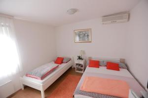 a bedroom with two beds with red pillows at Rooms Butković in Zagreb
