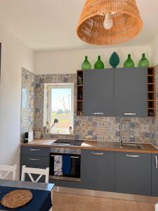 een keuken met grijze kasten, een wastafel en een raam bij Casa Mare Salento - a due passi dal mare in Marina di Lizzano