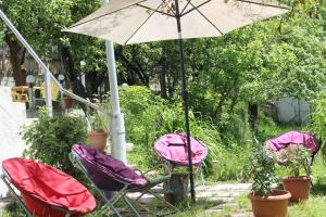 three chairs and an umbrella in a garden at Villa Gabliani in Mestia