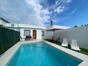 ein Swimmingpool mit zwei Stühlen und einem Sonnenschirm in der Unterkunft Casa Beatriz in Riumar