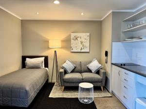 a bedroom with a bed and a couch and a table at Ashbrook Motel Taupo in Taupo