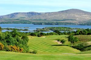 a golf course with a lake and mountains in the background at Gortnaboul House in Kilgarvan