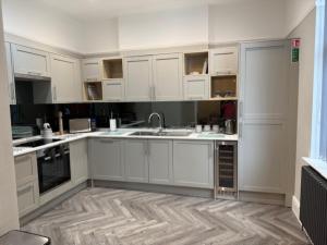 a kitchen with white cabinets and a wooden floor at Stylish 4 bed in Central Conwy in Conwy