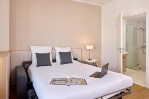 a bedroom with a bed with a laptop on it at Zenitude Hôtel Résidences Chessy in Chessy +17 photos