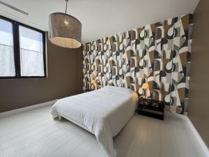 a bedroom with a bed and a patterned wall at Villa Terracotta - 11pers 24h du Mans - Rêve au Mans in Le Mans