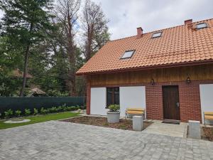 a brick house with two benches in a yard at Wczasowa 26 in Karwieńskie Błoto Drugie