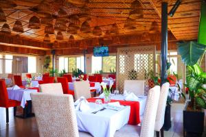 ein Esszimmer mit weißen Tischen und roten Stühlen in der Unterkunft Urban Park Suites Hotel in Kigali