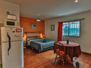 Un dormitorio con una cama, una mesa y un frigorífico. en Gala Austral, en Ushuaia