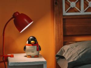 乌斯怀亚Gala Austral的一只玩具企鹅坐在床头柜上，旁边还有一盏灯