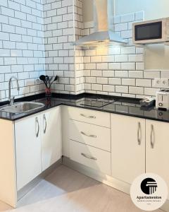 a kitchen with white cabinets and a sink at Apartamentos Basílica Santa Eulalia con Parking Gratis in Mérida +52 photos