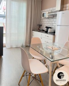 a kitchen with a glass table and chairs at Apartamentos Basílica Santa Eulalia PARKING GRATIS in Merida