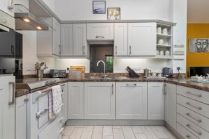 a kitchen with white cabinets and a sink at Willow at Gorslwyd - Sound Retreat in Aberporth +48 photos