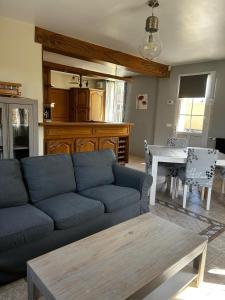 Una sala de estar con un sofá azul y una mesa. en Esprit Londonien - WIFI - TV -, en Bracquemont 2 fotos más