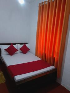 a bed with red pillows next to an orange curtain at Tea Leaf Family Cottage in Bandarawela