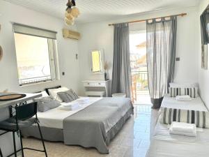 a bedroom with two beds and a desk and window at Giorgos concept suites AGAPI in Edipsos