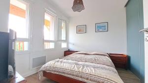 Un dormitorio con una cama y dos ventanas. en Euphrasie, en Lit-et-Mixe