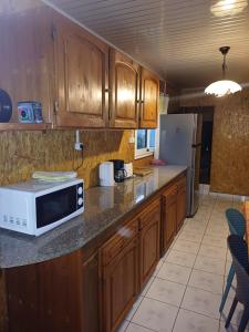 a kitchen with wooden cabinets and a microwave on a counter at L'Anthurium-Location Saisonnière 4Etoiles in Le Tampon