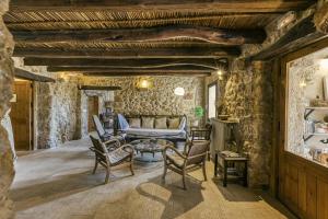 sala de estar con paredes de piedra, sofá y sillas en Mas Coquells Rural, en Vilanant