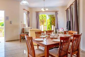 a dining room and living room with a table and chairs at Villa Gardenia by Villa Plus in Peyia