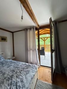 a bedroom with a bed and a sliding glass door at Vikendica Čardak in Srebrenik