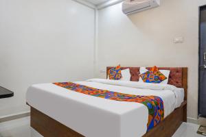 een slaapkamer met een groot bed met kleurrijke kussens bij FabHotel Bliss Executive - shaniwar wada in Pune
