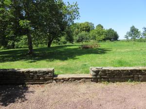 a stone wall in front of a grassy field at Le cellier d'halouze in Dol-de-Bretagne