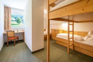 a bedroom with a bunk bed with a desk and a desk at Schi- und Wanderhotel Berghof in Bad Kleinkirchheim