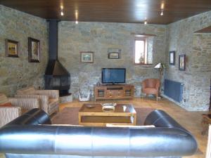 a living room with a leather couch and a tv at Casa da Paioca in Paleo