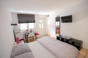 a bedroom with a white bed and a desk and a table at Rooms Butković in Zagreb