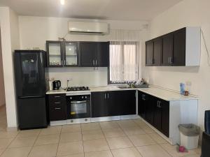cocina con armarios negros y nevera negra en Family Flat in San Gwann, en San Ġwann
