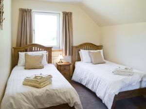 ein Schlafzimmer mit zwei Betten und einem Fenster in der Unterkunft March Cottage in Glenrossal + 4 Fotos