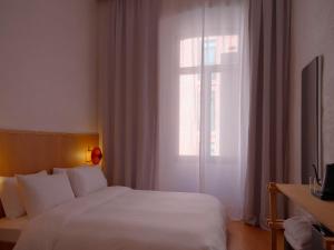 Un dormitorio con una cama blanca y una ventana. en Bellhop Tbilisi, en Tiflis