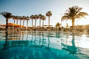 a swimming pool with palm trees in the background at Servatur Green Beach in La Playa de Arguineguín