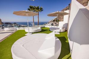 a white patio with white chairs and umbrellas at Servatur Hartaguna - Adults Only in Puerto Rico de Gran Canaria
