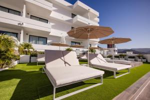 a group of chairs and umbrellas on the roof of a building at Servatur Hartaguna - Adults Only in Puerto Rico de Gran Canaria
