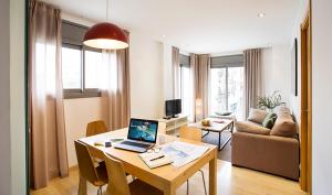 Una sala de estar con una mesa con una computadora portátil encima. en Durlet Rambla Mar Apartments, en Barcelona
