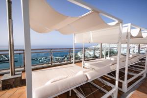 a balcony with white beds and the ocean at Servatur JB - Adults Only in Puerto Rico de Gran Canaria
